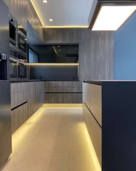 Cocina con mobiliario gris, iluminación LED y hornos empotrados